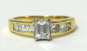 18ct diamond set ring with centre emerald cut stone and princess cut diamonds to the shoulders
