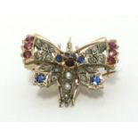 A antique butterfly brooch set with an arrangement of old cut diamonds, sapphires and ruby's, wing