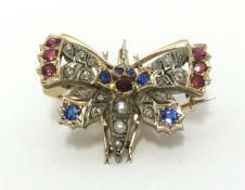 A antique butterfly brooch set with an arrangement of old cut diamonds, sapphires and ruby's, wing