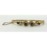 A yellow metal bangle set with amethyst and seed pearl approx 5.4gms.