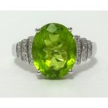 A 14k white gold and diamond ring set with an oval cut peridot, approx 3.56cts, diamond weight