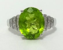 A 14k white gold and diamond ring set with an oval cut peridot, approx 3.56cts, diamond weight