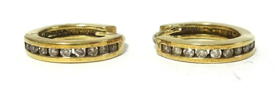 Pair of diamond channel set earrings set in yellow metal