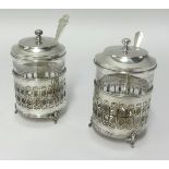 A pair of George V silver and glass jam pots, maker E.S.B, with spoons (not matching) height 11cm.