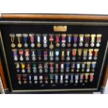 A collection of replica medal miniatures in three wall hanging frames, also loose and world map