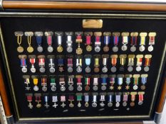 A collection of replica medal miniatures in three wall hanging frames, also loose and world map