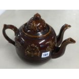 A Victorian twin spout treacle glazed teapot, height 23cm.