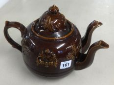 A Victorian twin spout treacle glazed teapot, height 23cm.