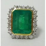 A large and impressive emerald and diamond cluster ring, the rectangular emerald approx 14mm x 10mm,