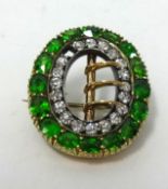 A diamond and green garnet? brooch, set in yellow gold, width 23mm (one stone missing).