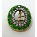 A diamond and green garnet? brooch, set in yellow gold, width 23mm (one stone missing).