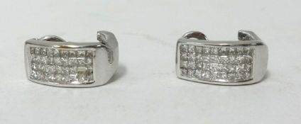 A pair of 14k white gold channel set diamond clip earrings (one stone missing).