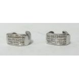 A pair of 14k white gold channel set diamond clip earrings (one stone missing).