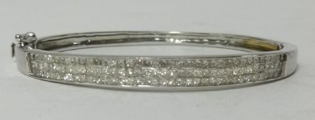 A modern 14k white gold channel set triple line diamond bangle, set with princess cut diamonds,