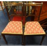 An Edwardian set of four mahogany and inlaid dining chairs.