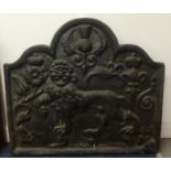 A heavy cast iron fire back on antique design, decorated with a lion, width 73cm, height 68cm.