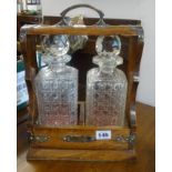 A two bottle Tantalus in a oak and silver plated mounted case.