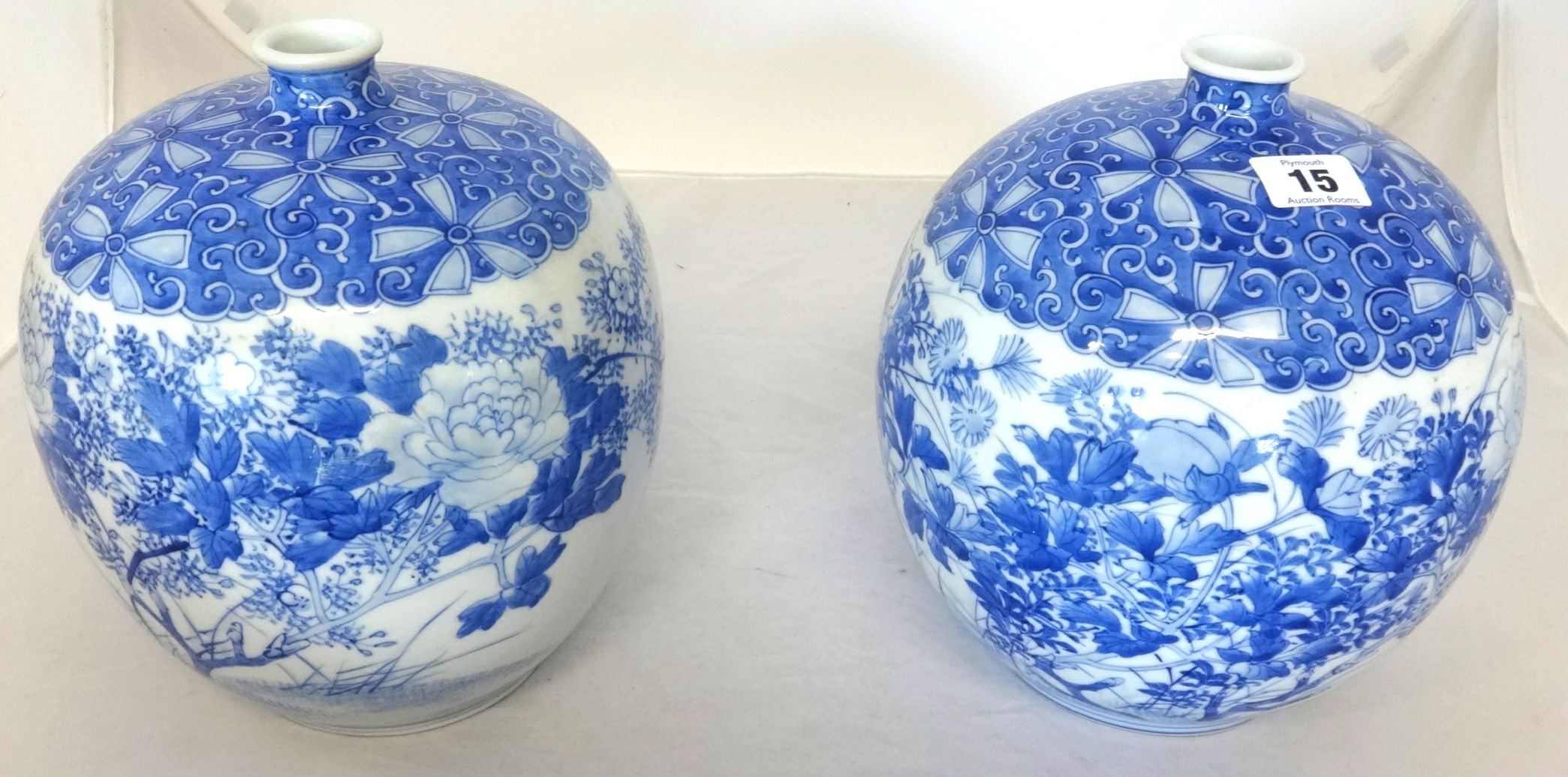 A pair of Japanese blue and white squat porcelain jars decorated with flowers.