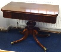 A Regency mahogany fold over card table on pedestal base with brass capped castors.