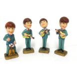 Four small, plastic figures of 'The Beatles'