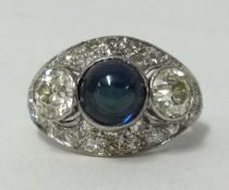 A platinum diamond cabochon sapphire ring set with three main stones within a pave diamond