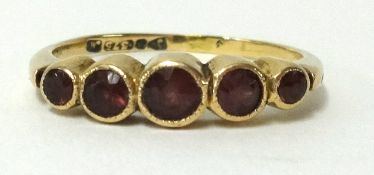 A 9ct five stone ring set with ruby coloured stones, finger size Q