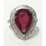 A 14k white gold and diamond ring set with a pear cut ruby (approx 7.50 carats), finger size N.