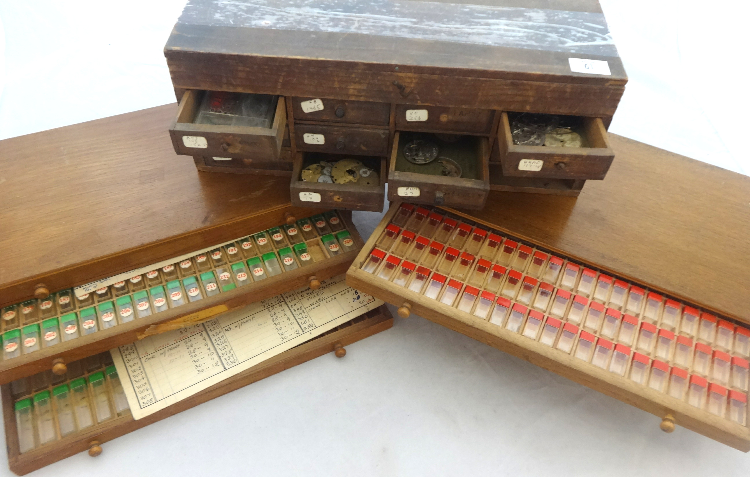 Two sets of small drawers containing various watch parts, movements, etc.