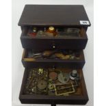 A small chest fitted with three drawers containing assorted watch parts, small tools, clamps etc.