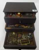A small chest fitted with three drawers containing assorted watch parts, small tools, clamps etc.