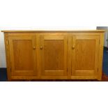 Ercol, a light wood sideboard fitted with three drawers and cupboards.