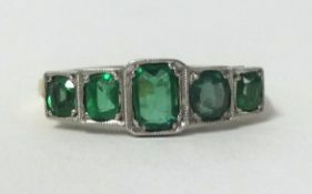 An antique 18ct gold and platinum five stone emerald ring, finger size O.