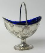 A Victorian silver sugar basket embossed with flowers, with swing handle and blue glass liner, maker