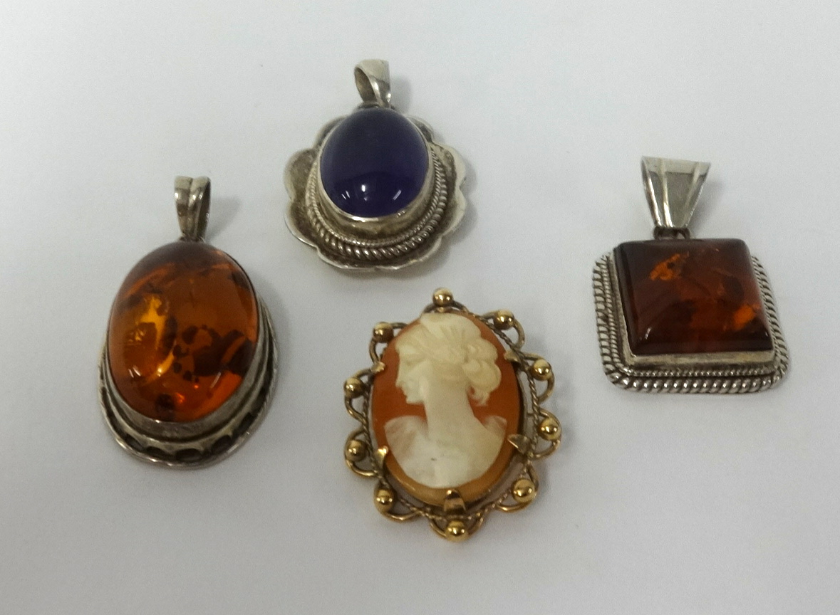 A 9ct gold cameo brooch, a purple hardstone pendant and two amber set pendants (4).