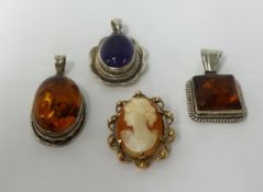 A 9ct gold cameo brooch, a purple hardstone pendant and two amber set pendants (4).