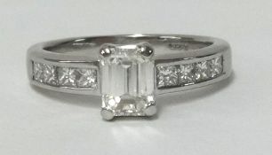 A fine diamond ring set in white gold, the emerald cut centre stone weighing approx 1.50cts, further