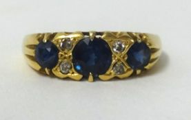 An 18ct three stone sapphire and diamond ring, finger size M.