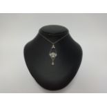 An art deco style diamond set drop pendant on fine chain, set with an arrangement of round and