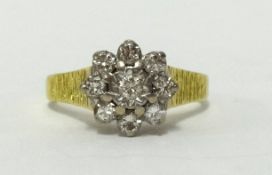 An 18ct nine stone diamond cluster ring, with bark effect shank, finger size Q.