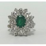 An 18ct emerald and diamond cluster ring, set in white gold, finger size J.