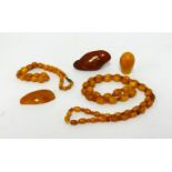 Amber, a bead necklace and bracelet and three carved amber stones, gross weight 103gms.