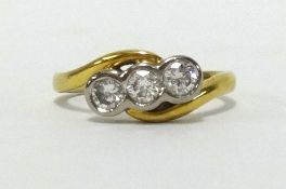 An 18ct three stone diamond cross over ring, finger size M.