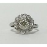 An 18ct white gold and platinum diamond daisy cluster ring with centre rub over setting with a round
