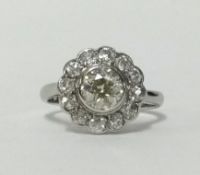 An 18ct white gold and platinum diamond daisy cluster ring with centre rub over setting with a round