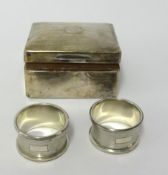 A pair of silver napkin rings and a silver cigarette box.