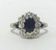 An 18ct white gold sapphire and diamond cluster ring, finger size K.
