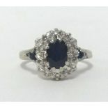 An 18ct white gold sapphire and diamond cluster ring, finger size K.