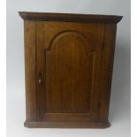 A Geo. III oak hanging corner cupboard with original green painted and shelved interior.