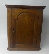 A Geo. III oak hanging corner cupboard with original green painted and shelved interior.