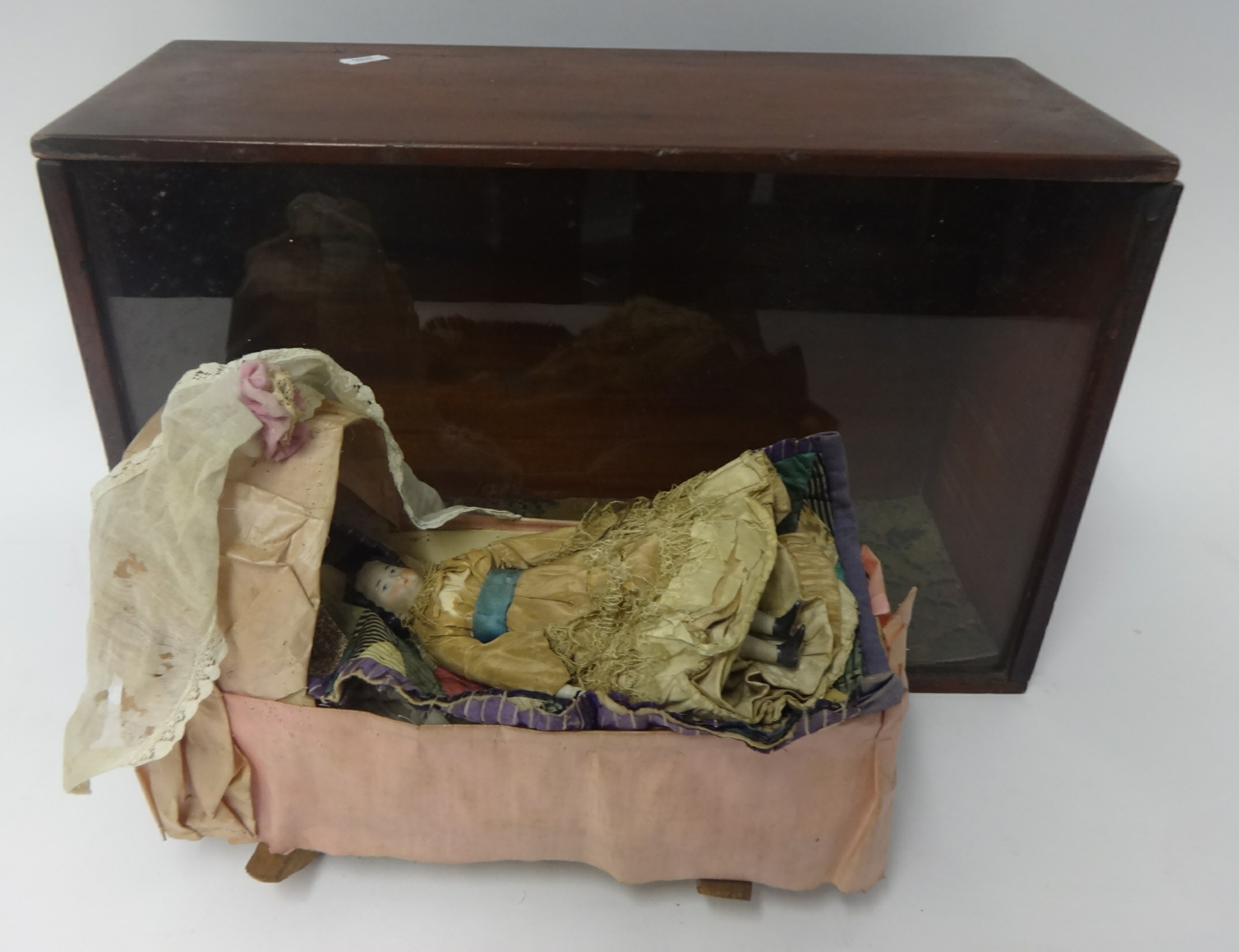 19th Century small doll with china head and shoulders and kid leather body with a rocking crib in